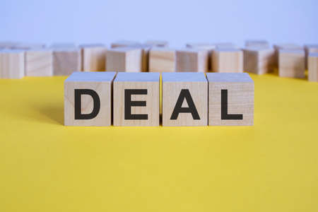 deal word on wooden building blocks lying on the yellow table, conceptの写真素材