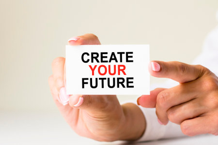 female hands hold card paper with text create your future on a white light background. business and finance conceptの写真素材