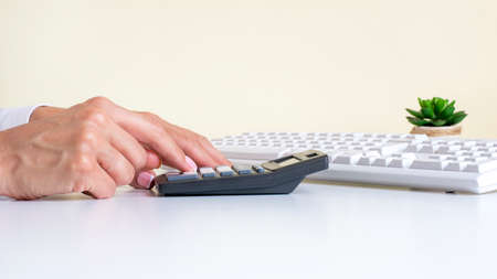 Businesswoman using black calculator in the office as she sits at her desk, close up view of her hands.の写真素材
