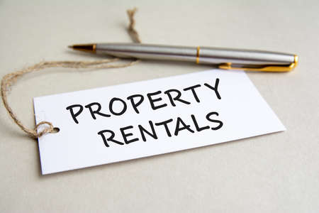 white card with text PROPERTY RENTALS with metal pen on gray backgroundの写真素材