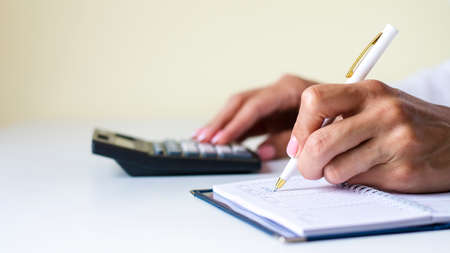 Close up cropped view of female sit by desk work with financial papers bills accounting taking notes...