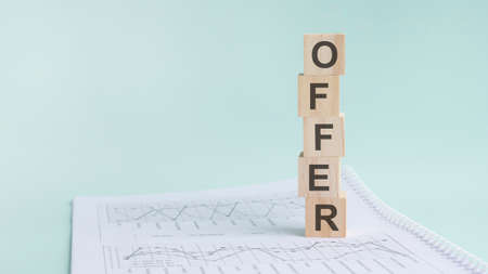 word OFFER with wood building blocks, light green background. document with numbers on background, business concept. space for text in left. front viewの写真素材