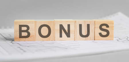 bonds is written on light wooden blocks. the word is located on a sheet with charts and graphs. business concept. gray backgroundの写真素材
