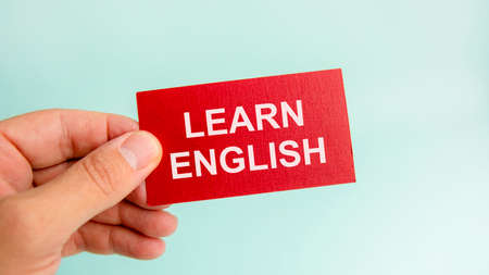 message on the red card with text learn english, in hands of businessman, conceptの写真素材