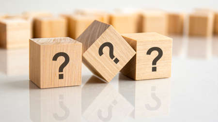 three question marks written on wooden cubes lying on the gray table, business and education concept. close-up cubesの写真素材