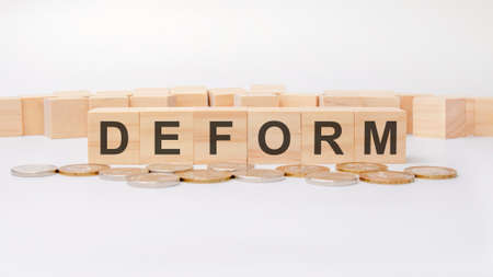 wooden block with the text Deform on boards. metal coins in the front field, investment conceptの写真素材