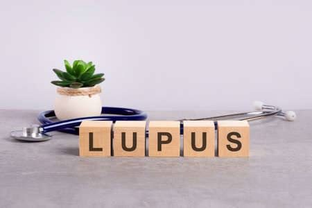 lupus word written on wooden blocks and stethoscope on light gray backgroundの写真素材