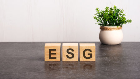 letters of the alphabet of esg on wooden cubes, green plant on a white background