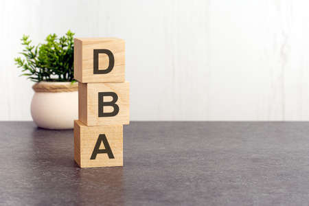 letters of the alphabet of dba on wooden cubes, green plant on a white background. dba - short for DataBase Administratorの写真素材