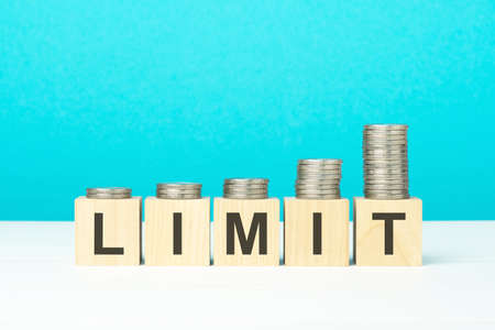 limit concept. wooden blocks with text and coins on white table. copyspace. bright blue background.の写真素材