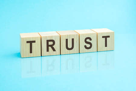 Trust - word written on wooden blocks. text is written in black letters and is reflected in the...
