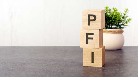 letters of the alphabet of PFI on wooden cubes, green plant, white background. PFI - short for Private Finance Initiativeの写真素材