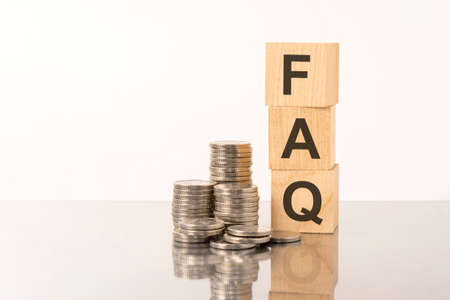 the word FAQ is laid out of wooden cubes with letters on white background with coins. FAQ - short for Frequency Asked Questionsの写真素材