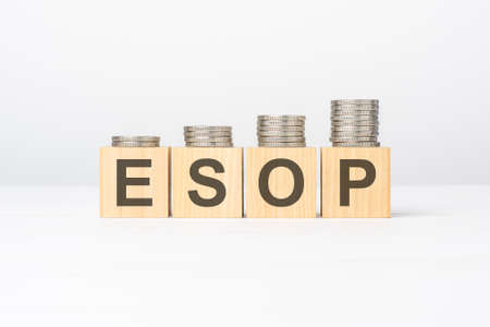 esop text written on wooden block with stacked coins on white background, business concept. esop - short for Employee Stock Ownership Planの写真素材