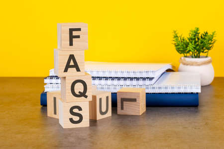 faqs word written on wooden cubes with copy space, yellow backgroundの写真素材