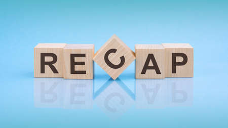 RECAP - word is written on wooden cubes close-up. blue background. white surface tableの写真素材