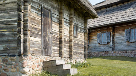 log facade of a typical rural house. old wooden windows with carved platbands. thatched roof....