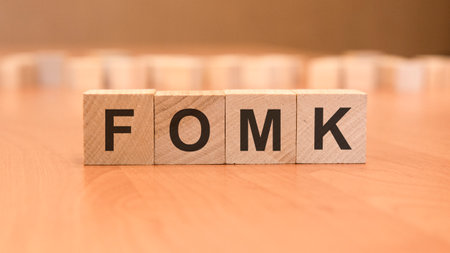 four wooden blocks with the letters Fomk - on the bright surface of a blue table. the inscription on the cubes is reflected from the surface. Federal Open Market Committeeの写真素材