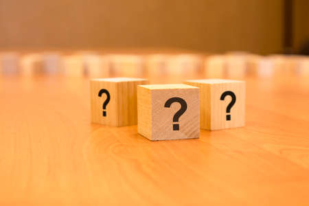cube with question mark on wooden background. space for text