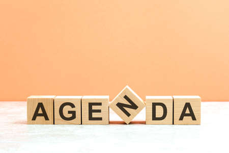 AGENDA text on a wooden blocks, gray table, orange background