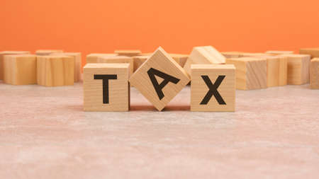TAX wooden blocks word on orange background. conceptの写真素材