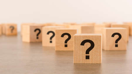 front view on many wood cubes with question marks. many question arising conceptの写真素材