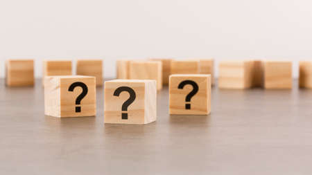 three wooden blocks with question marks on wooden table, closeup. space for text. wood backgroundの写真素材