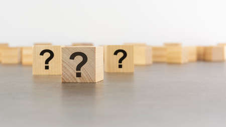 three wooden blocks with question marks on wooden table, closeup. space for text. wood backgroundの写真素材