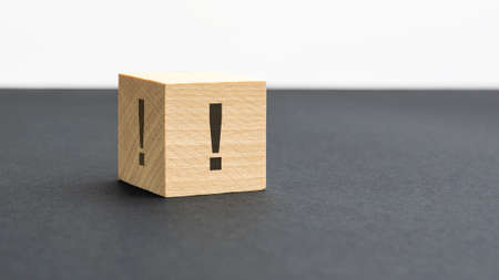 exclamation mark sign on a wooden block on a black background with copy space