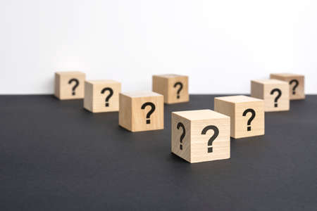 front view on many wood cubes with question marks. many question arising concept