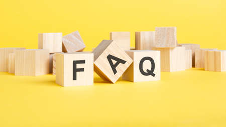 Wooden blocks with text FAQ on yellow baclground. frequently asked question conceptの写真素材