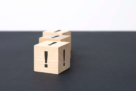 exclamation mark sign on a wooden block on a black background with copy space.