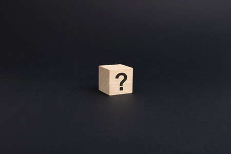 question mark on wooden block on black background with copy spaceの写真素材
