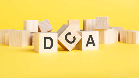 wooden blocks with text DCA on yellow background. Dollar Cost Averaging conceptの写真素材