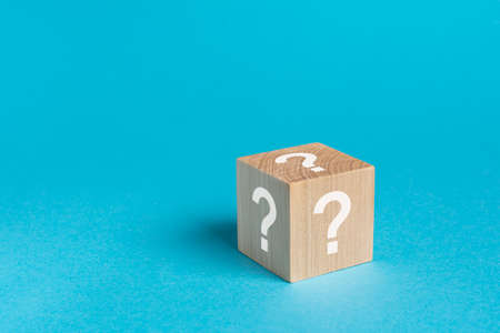 natural wooden cube with question white marks, bright blue backgroundの写真素材