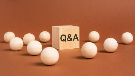 letters 'Q and A' on a wooden cube. brown background. wooden balls around. business conceptの写真素材