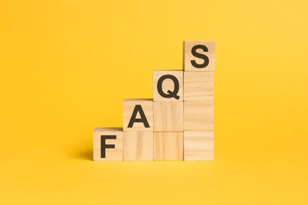 FAQS - text on wooden cubes, on yellow backgroundの写真素材