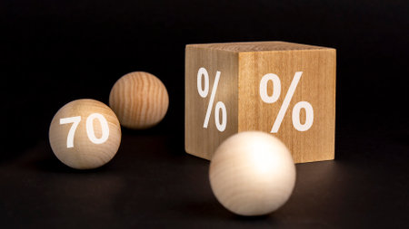 percent sign on wooden cube on black background with wooden balls. number 70 on wooden ball, concept...