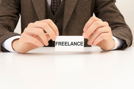 businessman hand holding paper card with text FREELANCE, business conceptの写真素材