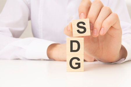 hand holding wood cube block with SDG text. Financial, Management, Economic, business concept.