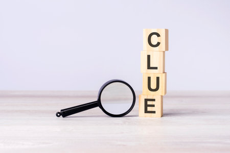 loupe and wooden blocks with text CLUE on wood table, gray background. copy spaceの写真素材