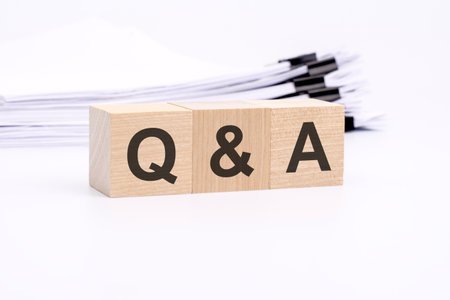 qa - text on wooden blocks. the background is a business papers. finance concept. white backgroundの写真素材