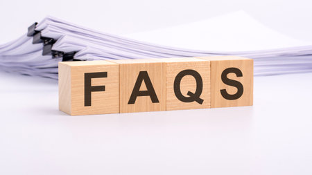 wooden blocks with text FAQS on white table, stack white paper on backgroundの写真素材