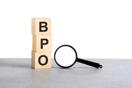 BPO - Business Process Outsourcing - text wooden cube blocks and magnifying glass on grey tableの写真素材