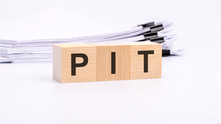 pit - text on wooden blocks. the background is a business papers. finance concept. white backgroundの写真素材