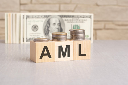 AML word on wooden cubes and US dollar bills background. Anti money laundering conceptの写真素材