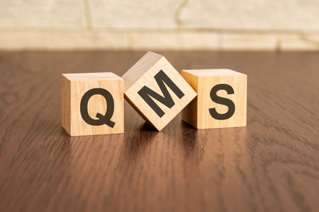 total quality management concept with TQM symbols on wooden cubes, dark wooden backgroundの写真素材