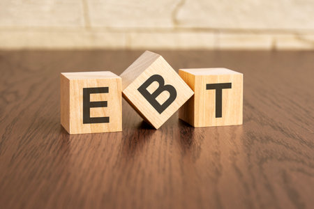 Earnings Before Taxes concept with symbols ebt on wooden cubes, dark wooden backgroundの写真素材