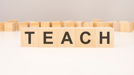 text TEACH made of wooden cubes and different wooden blocks on grey backgroundの写真素材