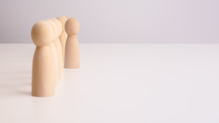 wooden men are displayed in a row on a light table, with free space for textの写真素材